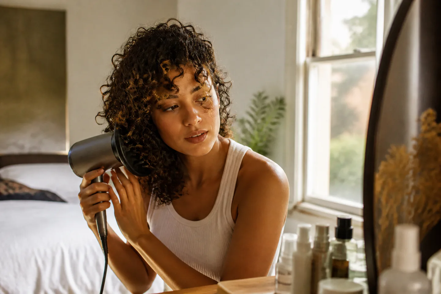 Woman using a diffuser hair dryer on naturally curly hair